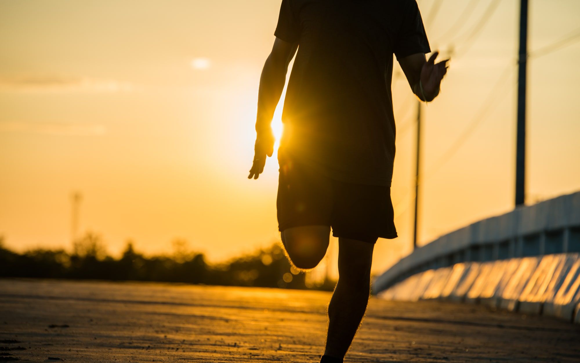 Silhouette of a man running at sunrise, warm light behind him