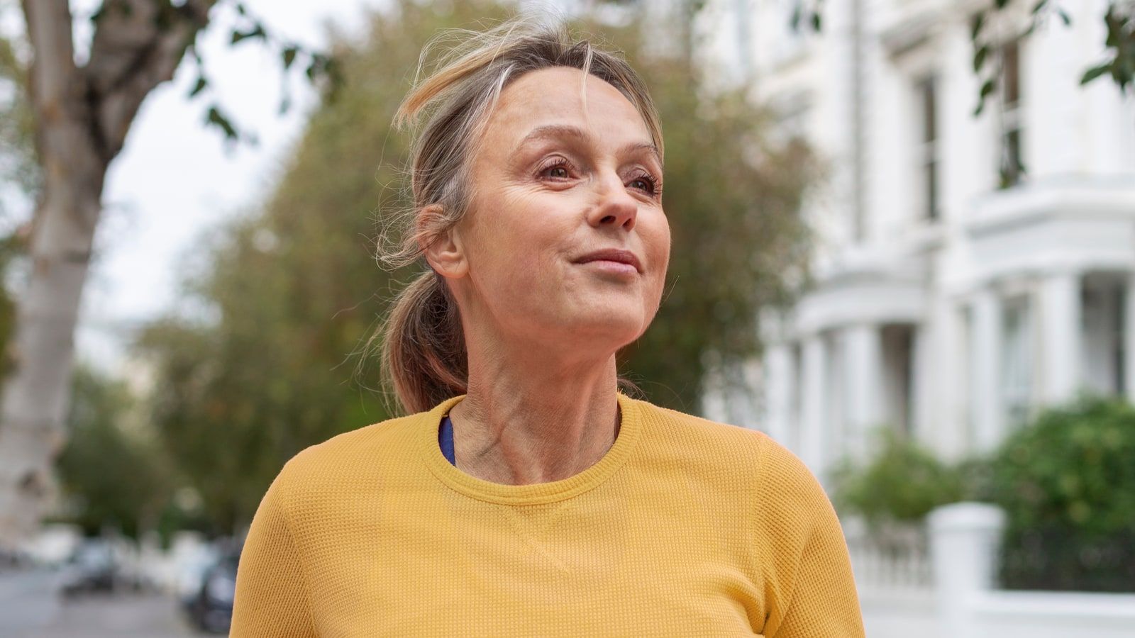 A woman jogging along a residential street, looking ahead